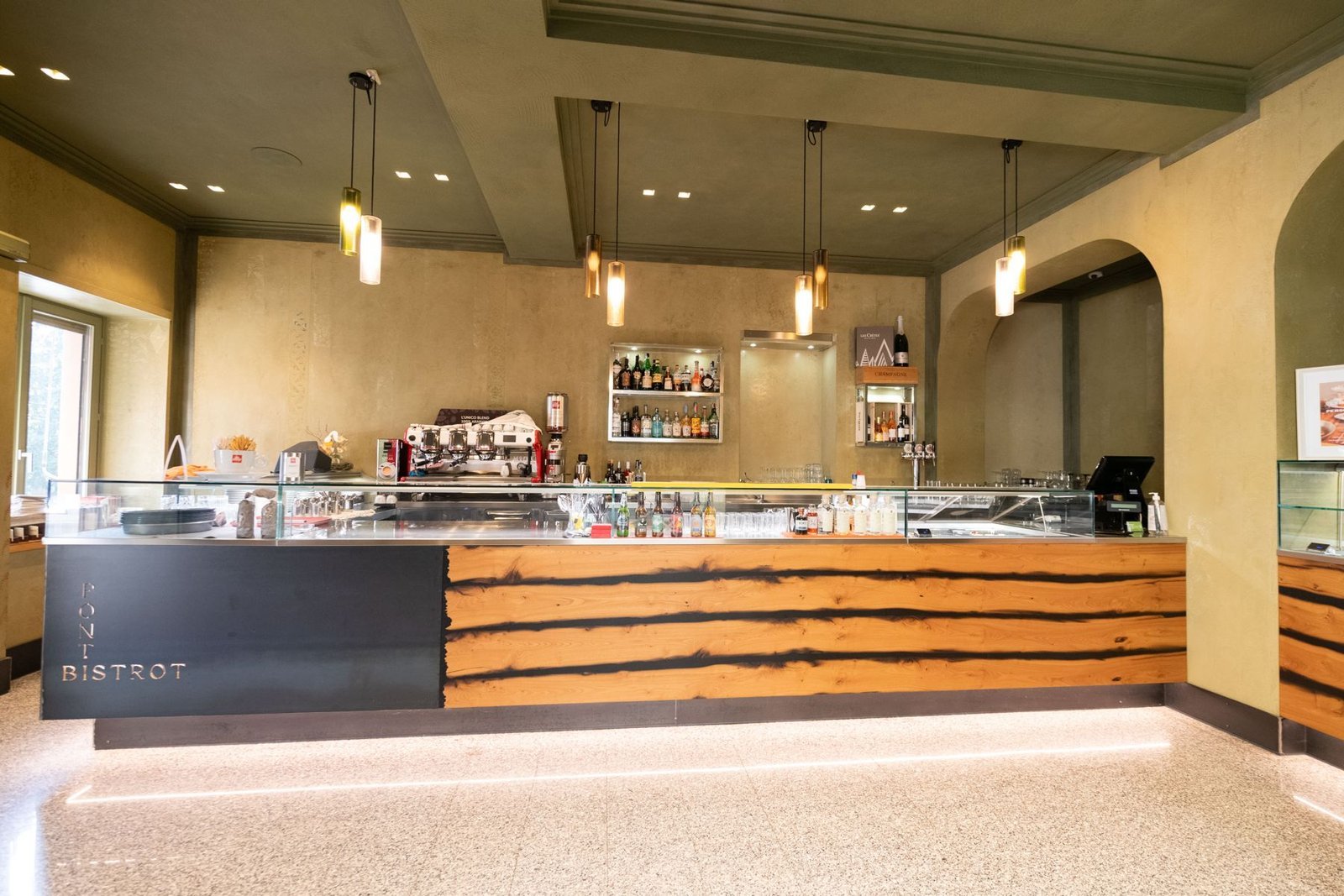 The Ponti Bistrot counter: wood with dark grain, an iron panel with the name, amber glass pendant lamps