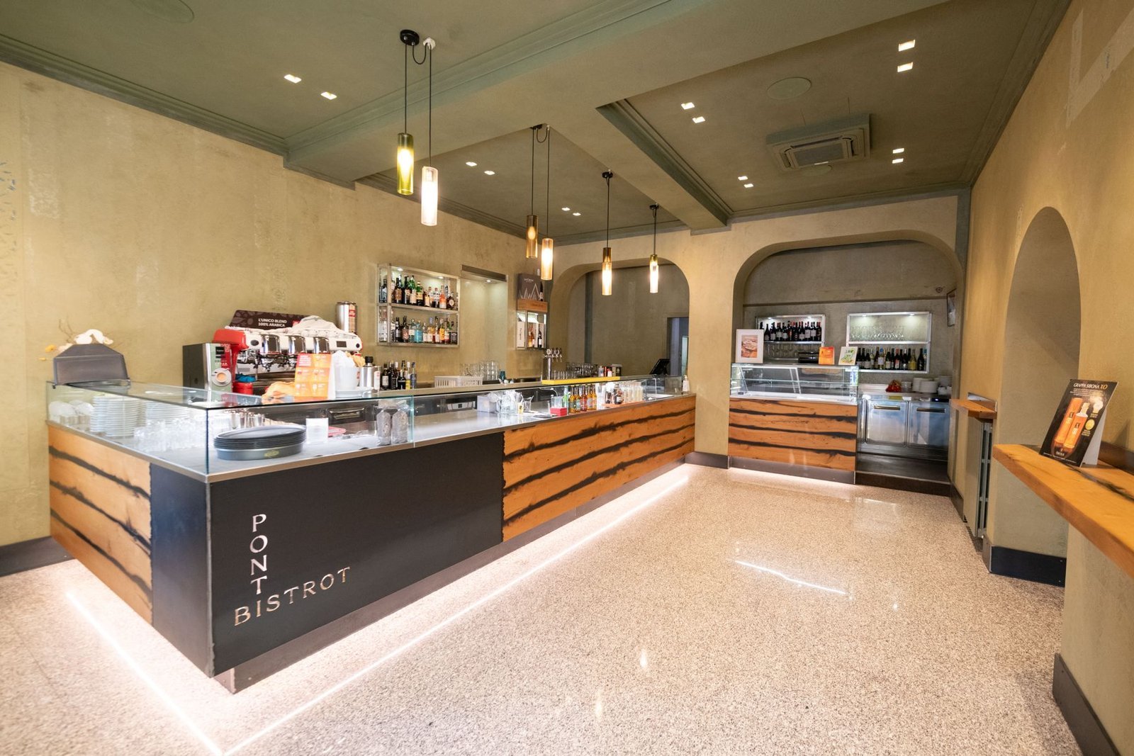The bistrot interior seen from the entrance: the corner counter and ochre walls