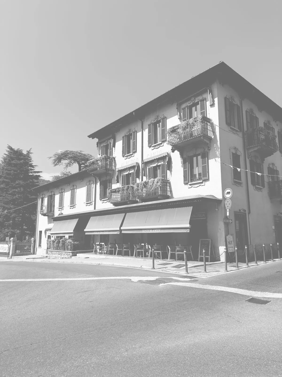 The bistrot building photographed in black and white, with awnings on the ground floor and balconies above